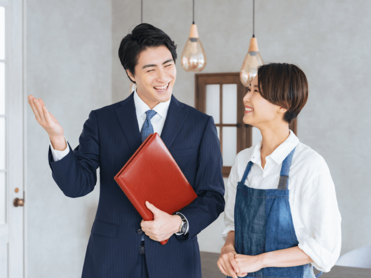 営業マンとエプロン姿の女性の笑顔の対話のイメージ